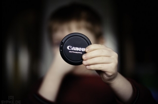 Kind hält Canon Objektivdeckel
